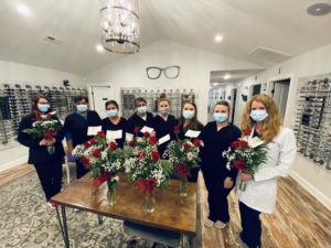 team at the eye site holding flowers and wearing masks