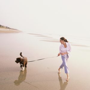 woman walking dog on the beach